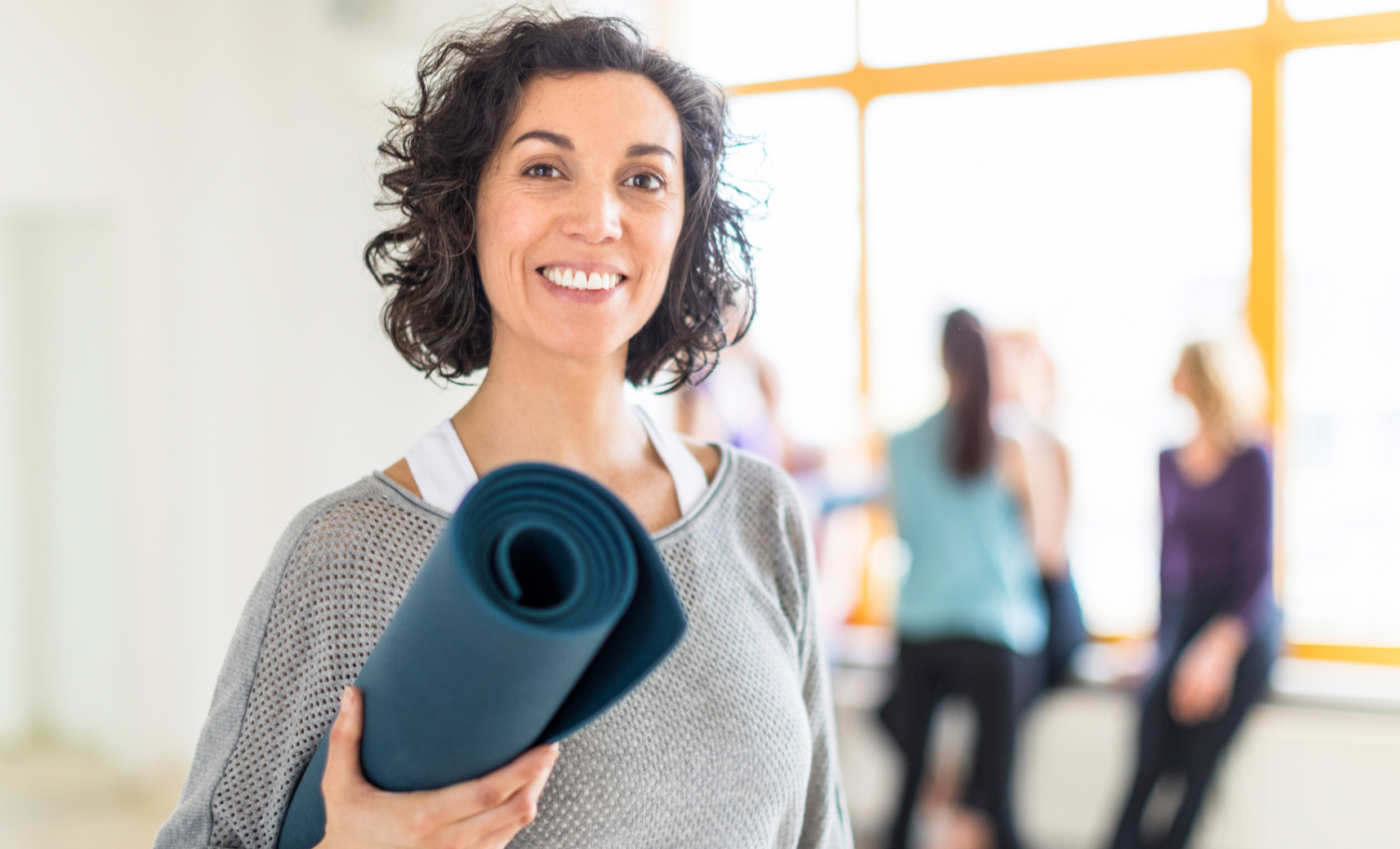 Lächelnde Frau mit Yoga-Matte